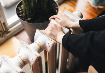 Ruka ženy kontroluje teplo na starším radiátoru Ruka ženy kontroluje teplo na starším radiátoru